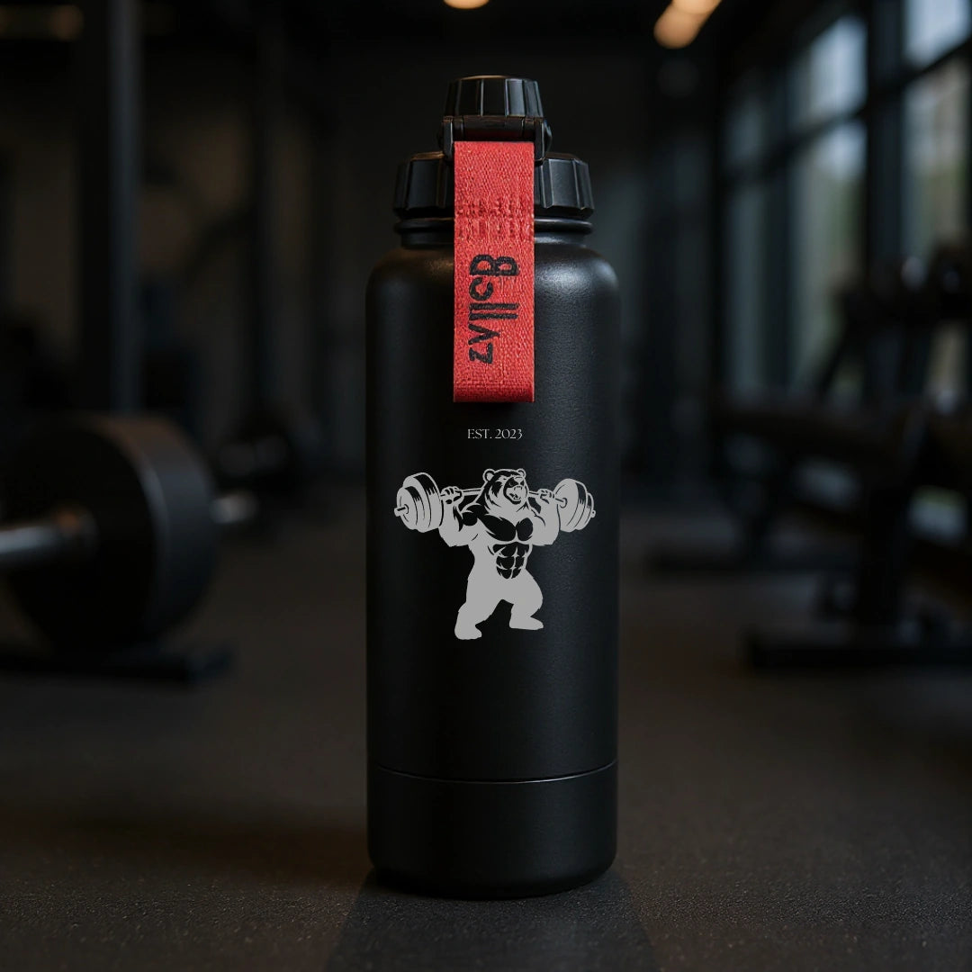 Bollaz Sport Edition Edelstahlflasche 1200 ml mit Gravur „Bear Barbell“ – isoliert (48 h kalt, 24 h warm), auslaufsicher, Quickslot-Trageschlaufe und mattschwarzem Finish. Perfekt für Bodybuilding, Krafttraining und einen starken, wilden Gym-Look.