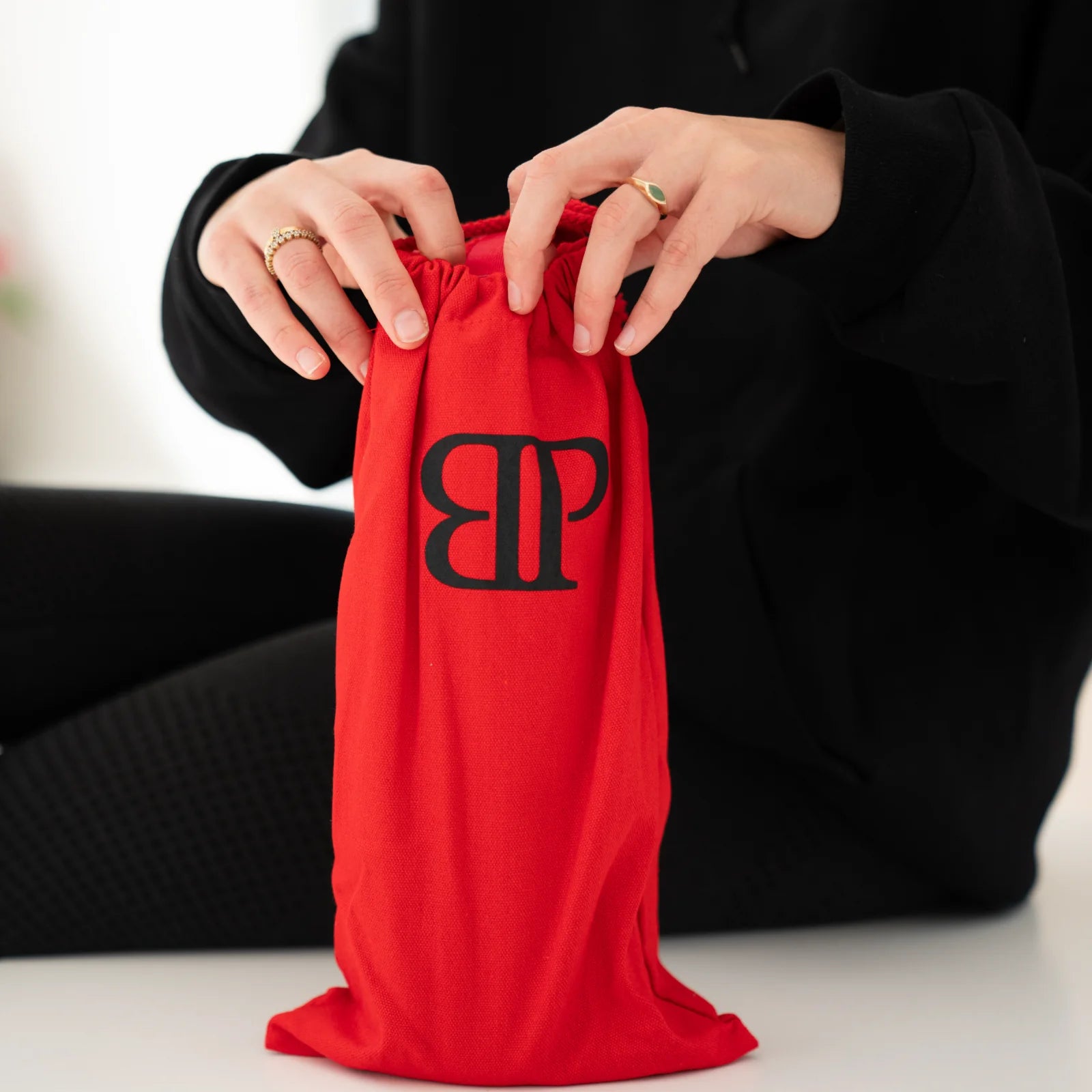 Rote Bollaz Stofftasche mit schwarzem BP Logo wird von zwei Händen geöffnet, hochwertige Premium-Verpackung fürs Shaker-Set.